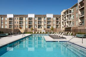 Council Bluffs apartment for rent - a swimming pool with lounge chairs in front of an apartment building