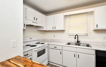 Travelers Rest apartment for rent - A kitchen with white cabinets and a wooden counter top.