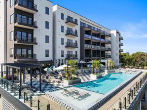 Houston apartment for rent - A large white building with a pool in front.