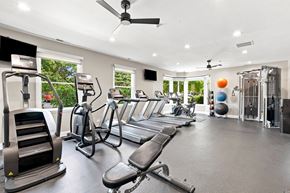 Naperville apartment for rent - A spacious gym with treadmills, elliptical machines, and a fan.