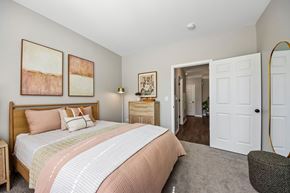 St. Charles apartment for rent - A bedroom with a large bed and a dresser with a mirror.