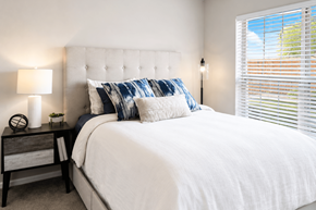 Lisle apartment for rent - A bedroom with a white bed and a nightstand with a lamp.
