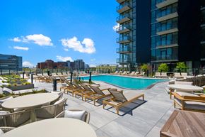 Chicago apartment for rent - a swimming pool with chaise lounge chairs and tables next to a tall building