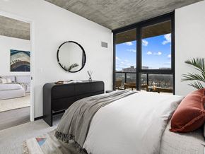 Chicago apartment for rent - A bedroom with a large bed and a view of the city.