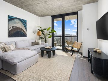 Chicago apartment for rent - A living room with a grey couch, a black coffee table, and a painting on the wall.