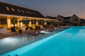 Spring townhouse for rent - A swimming pool in front of a building with a sun lounger.