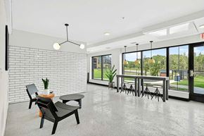 Woodbury townhouse for rent - Bright apartment community lounge with polished concrete floors, modern seating, white tile accent wall, and large windows with views of green outdoor space.