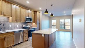 Lincoln apartment for rent - a kitchen with a large central island featuring tan wooden cabinets and light quartz countertops