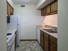 Lincoln apartment for rent - A kitchen with wooden cabinets, white appliances, and a passthrough counter top open to the living room.