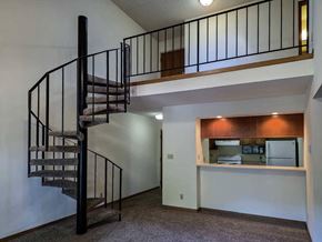 Lincoln apartment for rent - A living room with a pass through counter to the kitchen, and a spiral staircase with a metal railing to the loft area above.