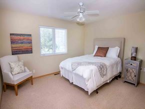 Lincoln triplex for rent - a bedroom with a white bed and a ceiling fan