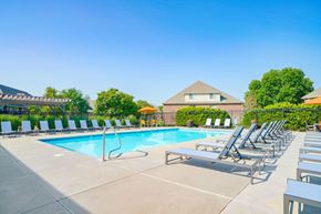 Lincoln apartment for rent - a swimming pool surrounded by rows of lounge chairs with an apartment building in the background