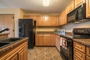 Omaha triplex for rent - a kitchen with black appliances and wooden cabinets