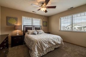 Omaha triplex for rent - a bedroom with a queen bed, dark wood furniture, and a ceiling fan
