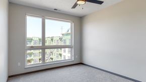 Lincoln apartment for rent - Bedroom with large window and ceiling fan in the Melody floor plan at Haven at Uptown in Lincoln, NE