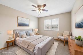 Lincoln apartment for rent - Virtually staged bedroom with a large bed, an accent chair, a ceiling fan, and a window bringing natural light into the space.