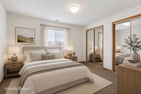 Lincoln apartment for rent - Bright, virtually staged apartment bedroom with neutral carpeting, mirrored closet doors, wood trim, and a large window with natural light.