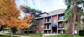 Lincoln apartment for rent - A red brick building with a blue awning and a tree with orange leaves in front.