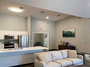 Lincoln apartment for rent - a modern kitchen with white cabinets and stainless steel appliances in a clubhosue with a coffee bar and grey couch