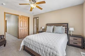 La Vista townhouse for rent - A bedroom with a large bed, a ceiling fan, and a nightstand with a lamp.