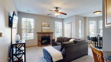 Omaha townhouse for rent - a living room with a couch and a fireplace and a ceiling fan