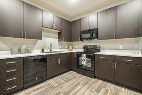 Omaha apartment for rent - Traditional design kitchen with dark cabinetry, quartz countertops in Blackstone District Omaha