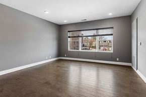 Omaha apartment for rent - Expansive apartment living room features wood-look flooring, gray walls, and a broad window overlooking the surrounding community.