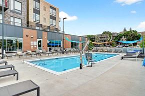 Eagan townhouse for rent - A large outdoor swimming pool surrounded by sun loungers and a building in the background.