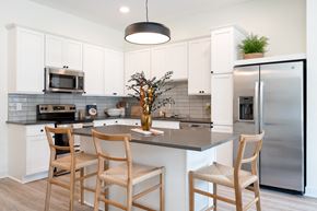 Eagan townhouse for rent - Kitchen with white cabinets and stainless steel appliances three wooden chairs surrounding kitchen island