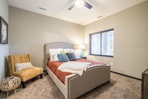 Omaha townhouse for rent - A bedroom with a bed, chair, and window.