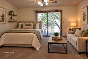 Lincoln apartment for rent - Virtually staged apartment bedroom with a seating area, carpet, ceiling fan, and sliding balcony doors.