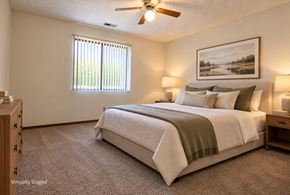 Lincoln apartment for rent - Virtually staged apartment bedroom with neutral finishes, a large window, carpeted flooring, and a ceiling fan.