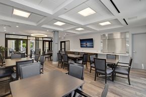 Frederick apartment for rent - a common room with tables and chairs and a television on the wall