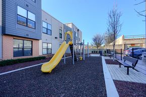 Baltimore apartment for rent - A playground with a yellow slide in front of a building.