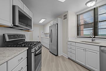 Baltimore apartment for rent - A modern kitchen with white cabinets and appliances.