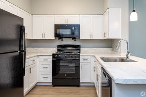 Edgewood apartment for rent - a kitchen with white cabinets and black appliances