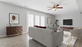 Lexington Park apartment for rent - A living room with a grey couch, a brown side table, and a ceiling fan.