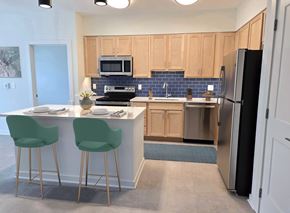 Baltimore apartment for rent - A kitchen with a white counter and green chairs.