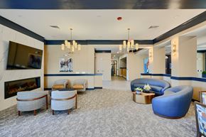 Baltimore apartment for rent - Now leasing senior 1-bedrooms in Baltimore, MD. A spacious lobby with a fireplace, chairs, and a blue armchair.