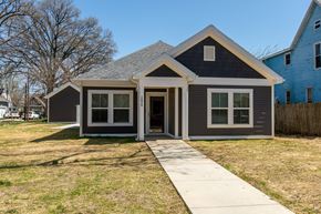 Evansville apartment for rent - Charming single-story home with a welcoming front entrance, large windows, and a simple lawn under a clear sky.