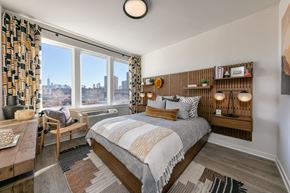 Jersey City apartment for rent - A bedroom with a large bed and a view of the city.