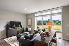 Cleveland apartment for rent - A living room with a black couch, a wooden coffee table, and a large window with a view of the outdoors.