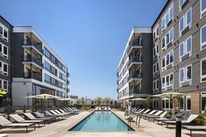 Cleveland apartment for rent - A swimming pool surrounded by lounge chairs and umbrellas in front of apartment buildings.