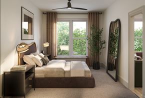 Charlotte apartment for rent - A bedroom with a large bed, a ceiling fan, and a view of the outdoors through the window.
