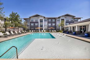 San Antonio apartment for rent - a swimming pool with lounge chairs and umbrellas in front of an apartment building