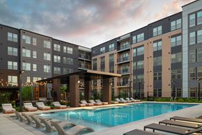 Woodbridge apartment for rent - A modern apartment complex with a pool and lounge chairs.