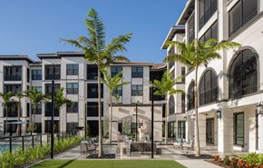 Venice apartment for rent - A row of modern buildings with a pool and palm trees in front.