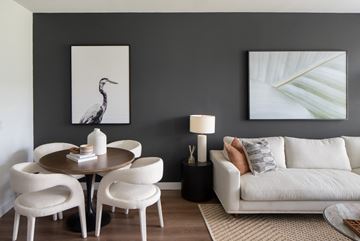Sanford apartment for rent - A living room with a white couch, a round table with four chairs, and two framed pictures on the wall.