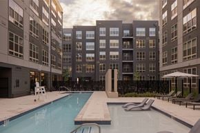 Hyattsville apartment for rent - A swimming pool in front of a building with a sunset in the background.