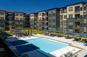 Austin apartment for rent - A swimming pool surrounded by apartment buildings and lounge chairs.